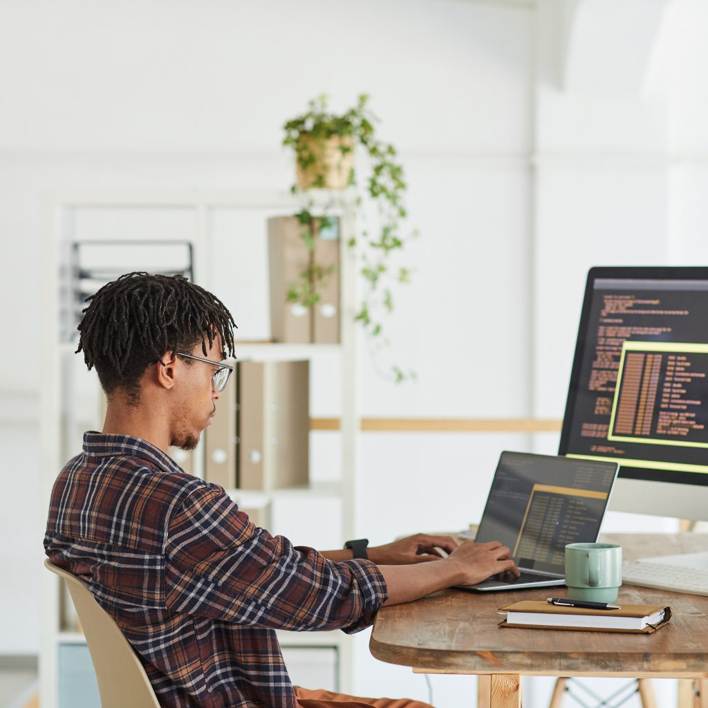 Person coding at desk with dual screens