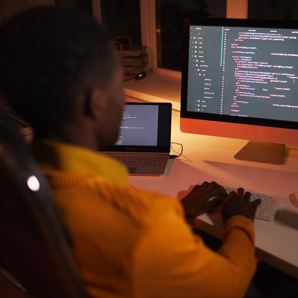 Person coding at desk with laptop and monitor