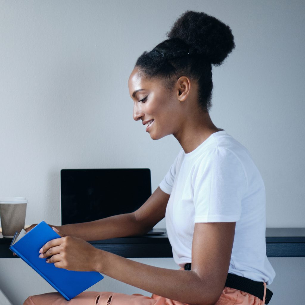 Woman reading blue notebook at desk