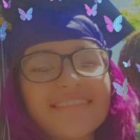 Smiling graduate with purple hair and butterflies